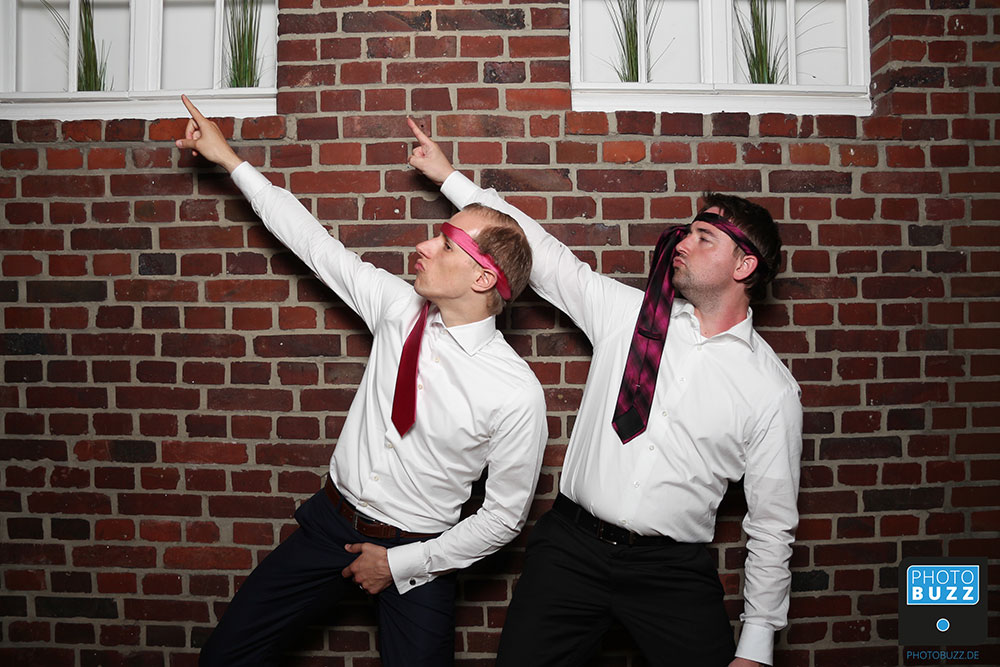 Zwei Personen (m/m) mit Krawatten um die Stirn gebunden machen ein Foto mit der Fotobox.